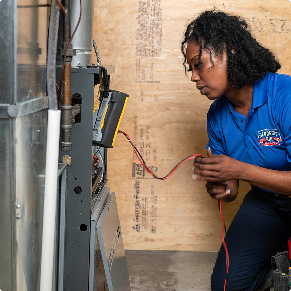 Academy Air technician testing wiring on a home furnace