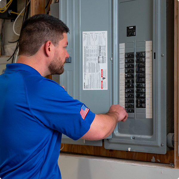 Academy Air electrician working inside an open electrical breaker panel