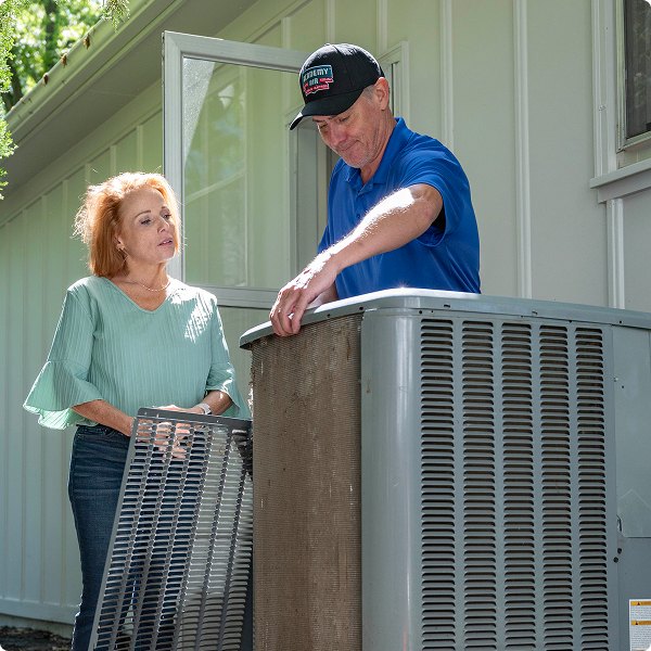 Academy Air technician and a homeowner standing beside an outdoor air conditioner