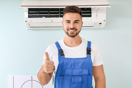Male technician showing a thumbs-up after repairing an air conditioner in a residential home in St. Louis, MO.