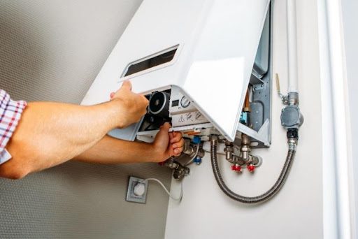 A professional water heater repair expert taking the cover off a tankless water heater that requires an inspection in Creve Coeur, MO.